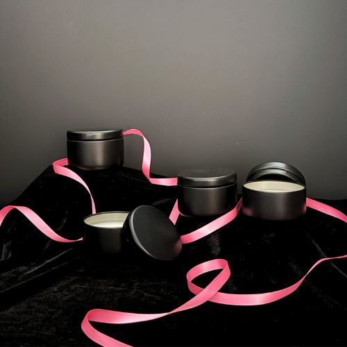 Black containers with pink ribbons on a dark surface
