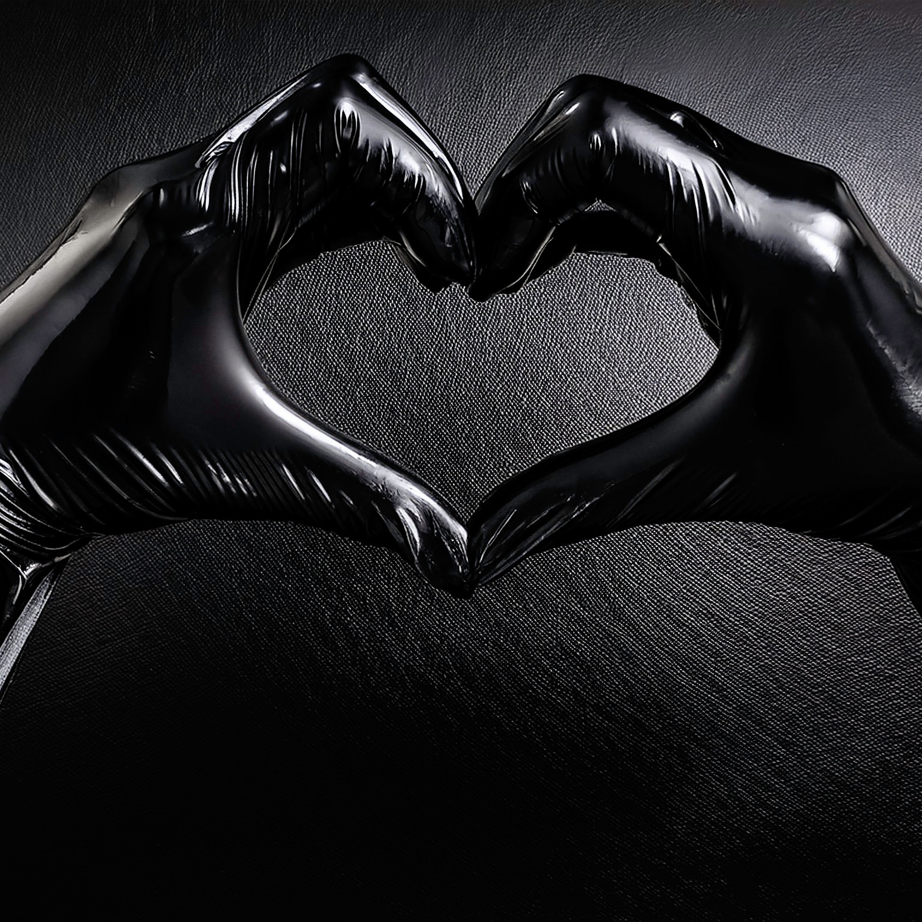 Hands in black latex gloves forming a heart shape