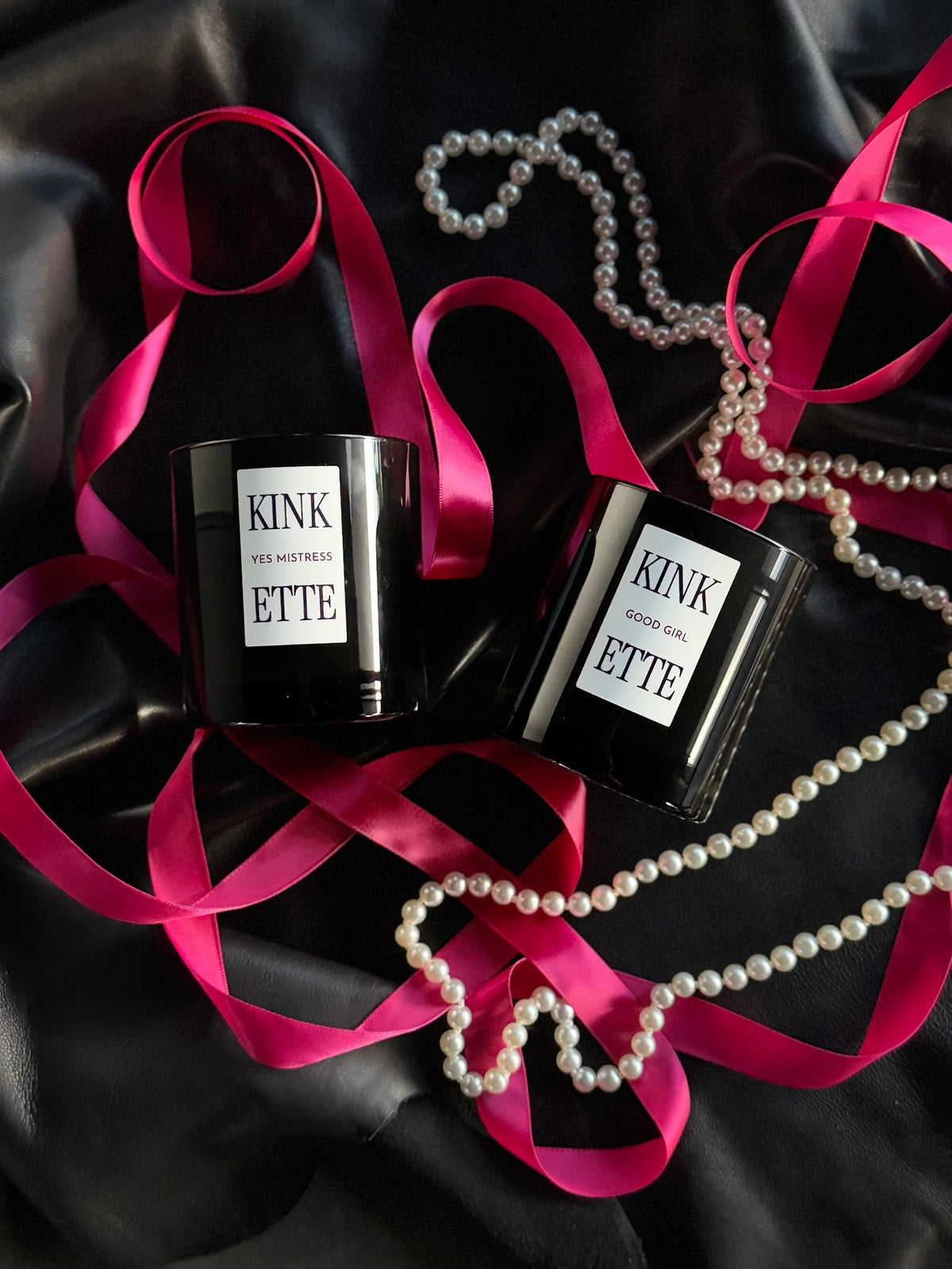 Four candles against a black background with a leather flogger and a lighter