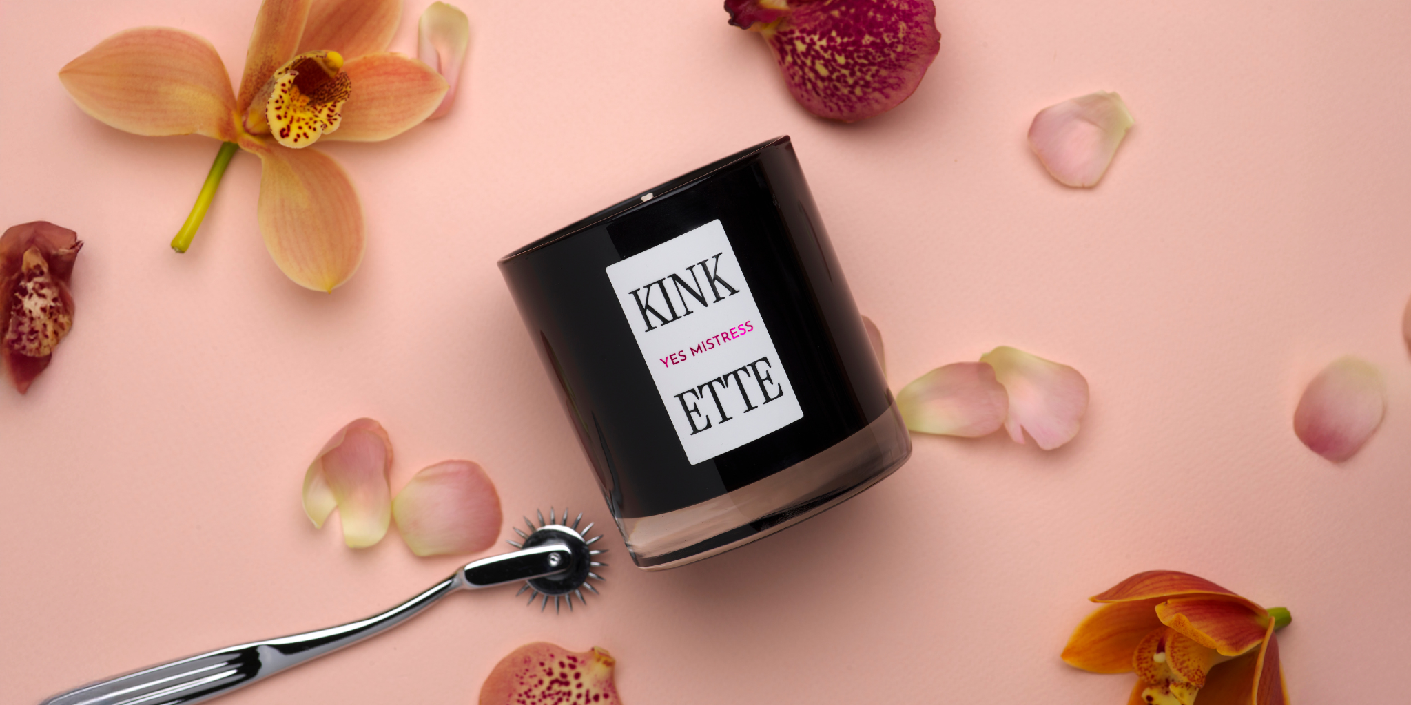 Kinkette candle with Wartenberg wheel on blush pink background with scattered orchids — What is Kink to Us