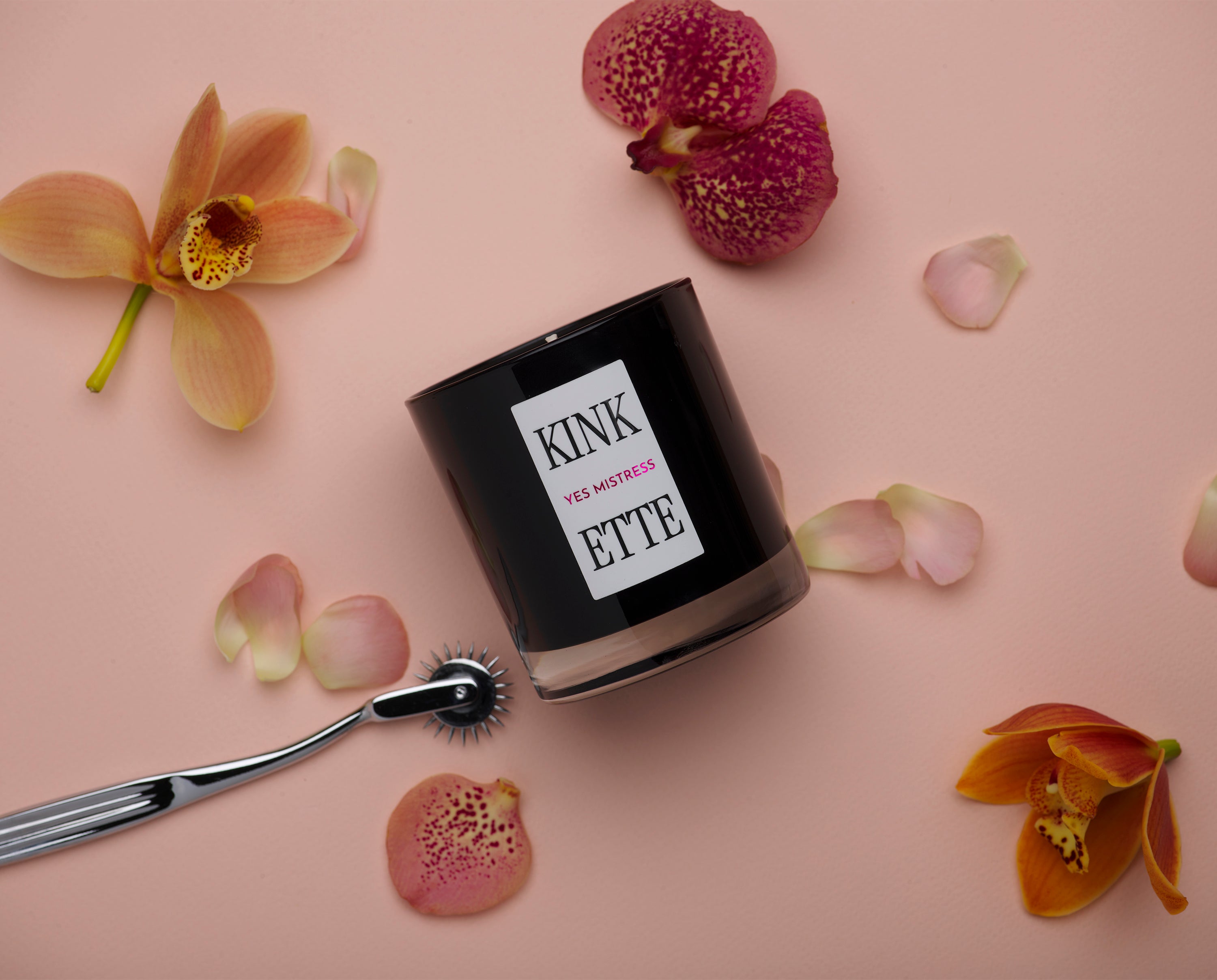 Kinkette candle with Wartenberg wheel on blush pink background with scattered orchids